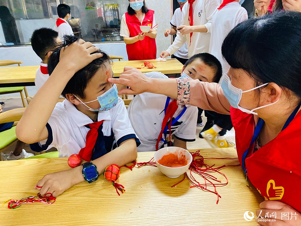 5月31日，在江西省南昌市灣里四小的教室里，志愿者給孩子們用雄黃畫(huà)額。通過(guò)互動(dòng)活動(dòng)，讓留守兒童度過(guò)了一個(gè)溫馨難忘的節(jié)日。人民網(wǎng) 時(shí)雨攝