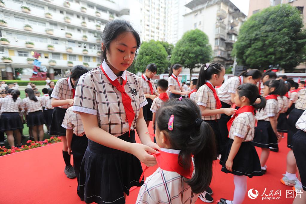 5月31日，在廣西壯族自治區(qū)南寧市民主路小學(xué)，高年級(jí)同學(xué)在為新隊(duì)員佩戴紅領(lǐng)巾。人民網(wǎng)記者 嚴(yán)立政攝