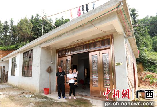 7月4日，在廣西柳州市融安縣大坡鄉(xiāng)崗偉村，脫貧戶肖裕安（左）與妻子、外孫在改造后的房屋前合影。覃慶和 攝