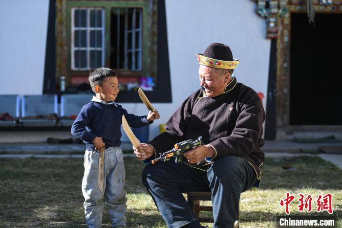圖為米林縣扎西繞登鄉(xiāng)彩門村64歲的洛桑帶著孫子巴桑在院子的草地上玩耍?！『闻罾?攝